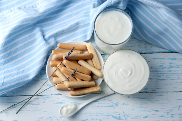 Homemade yogurt and tasty sweet bread sticks on wooden table background — Stock Photo, Image