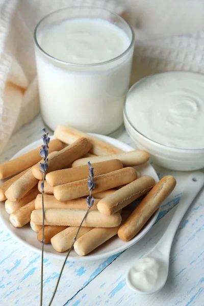 Homemade yogurt and tasty sweet bread sticks on wooden table background — Stock Photo, Image
