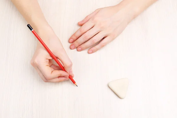 Tangan manusia dengan pensil dan menghapus karet pada latar belakang meja kayu — Stok Foto