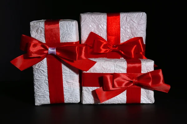 Hermosos regalos con cintas rojas, sobre fondo oscuro — Foto de Stock