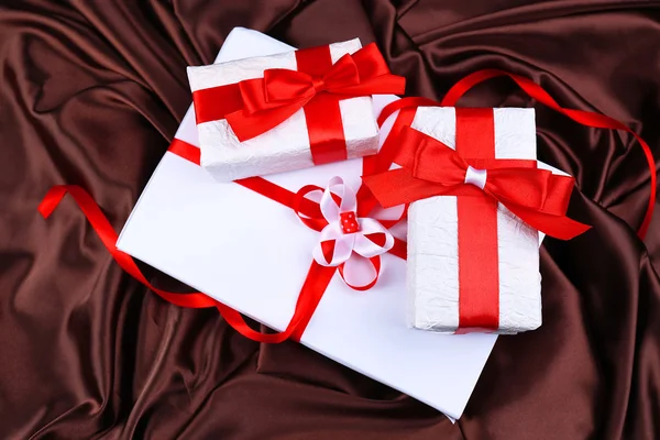 Belos presentes com fitas vermelhas no fundo de seda — Fotografia de Stock
