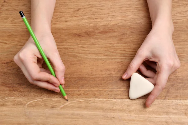 Manos humanas con lápiz y goma de borrar sobre fondo de mesa de madera —  Fotos de Stock
