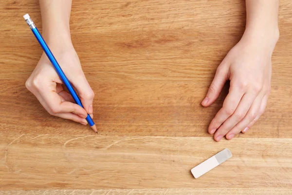 Insan eli ile ahşap masa arka plan üzerinde kalem ve silme lastik — Stok fotoğraf