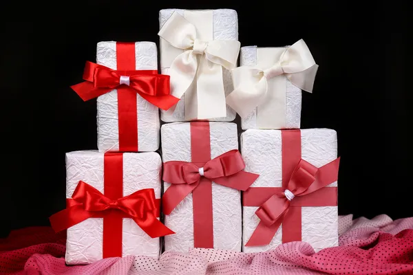 Beautiful gifts with red ribbons on dark background — Stock Photo, Image