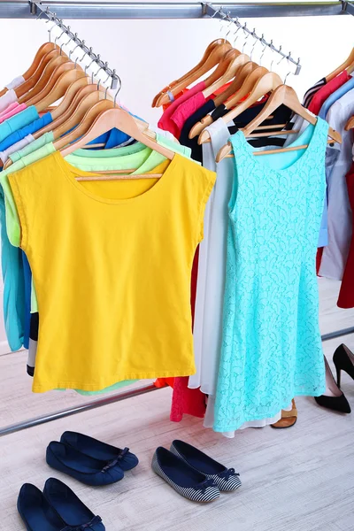 Verschillende kleding op hangers en schoenen op lichte achtergrond — Stockfoto