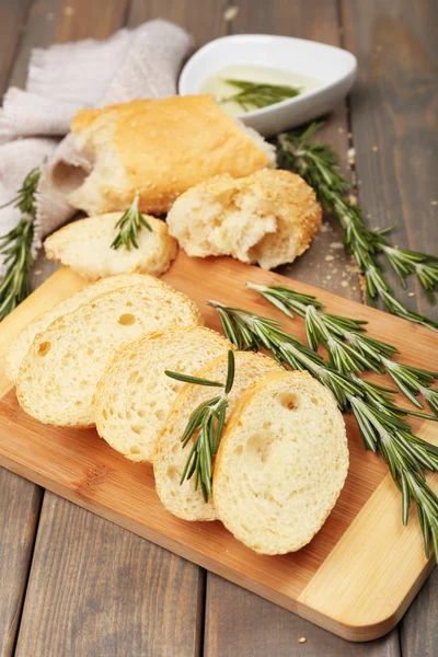 Färskt bröd med olivolja och rosmarin på träbord — Stockfoto