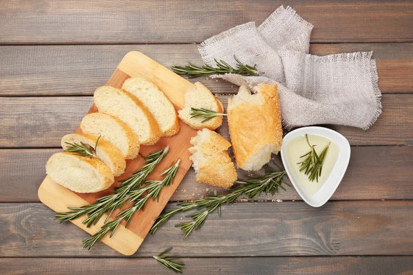 Fresh bread with olive oil and rosemary on wooden table — Stock Photo, Image