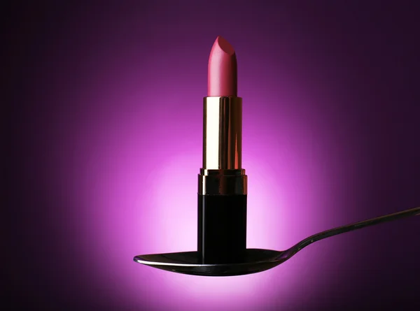 Lipstick in silver spoon on purple background — Stock Photo, Image