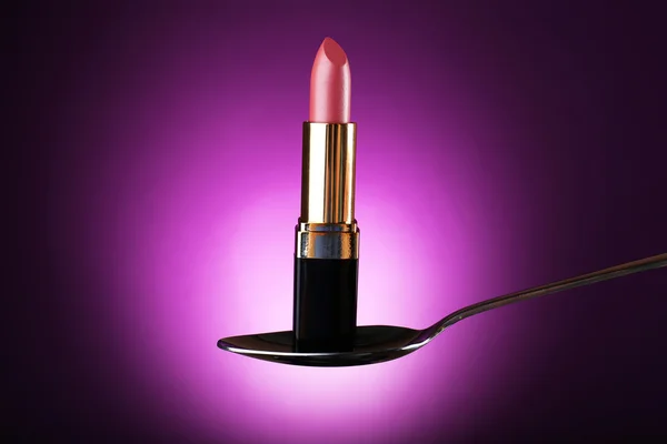 Lippenstift in silbernem Löffel auf lila Hintergrund — Stockfoto