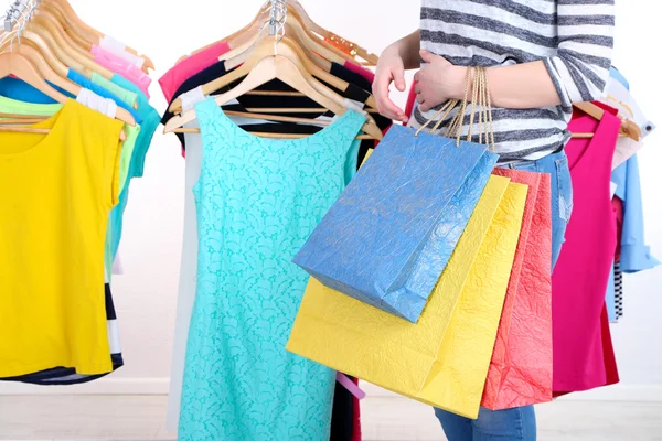 Jovem mulher escolher roupas perto de rack com cabides — Fotografia de Stock