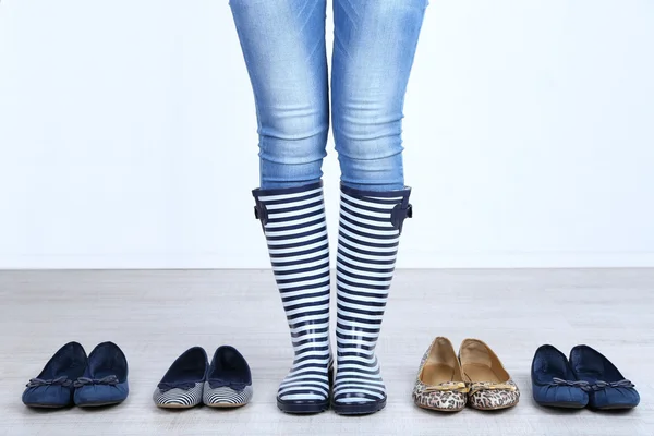 Meisje kiest schoenen in de kamer op grijze achtergrond — Stockfoto