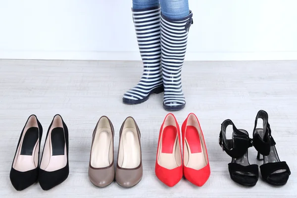 Ragazza sceglie scarpe in camera su sfondo grigio — Foto Stock