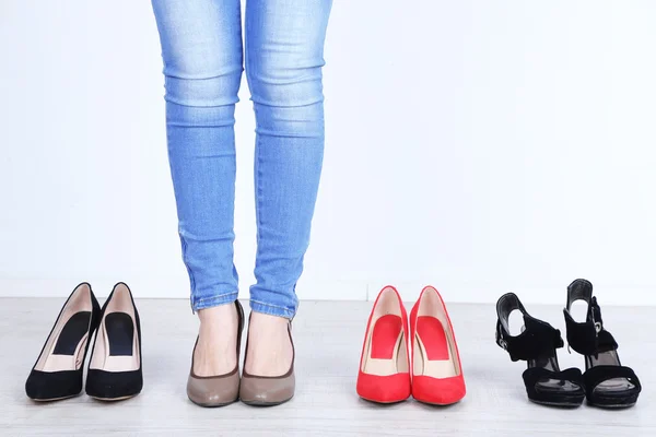 Mädchen wählt Schuhe im Zimmer auf grauem Hintergrund — Stockfoto