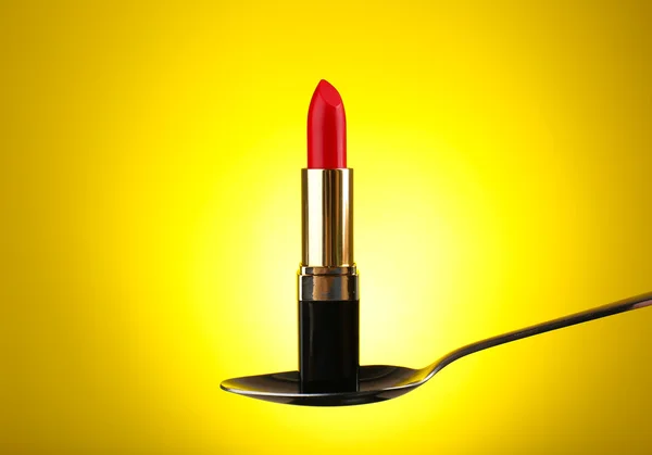 Lipstick in silver spoon on yellow background — Stock Photo, Image