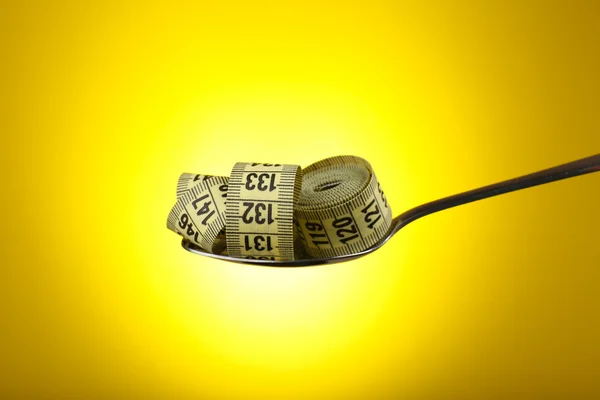 Measuring tape in silver spoon on yellow  background — Stock Photo, Image