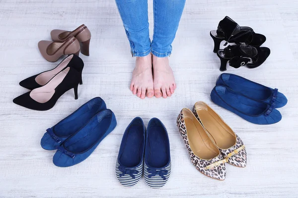 Девушка выбирает обувь в комнате на сером фоне — стоковое фото