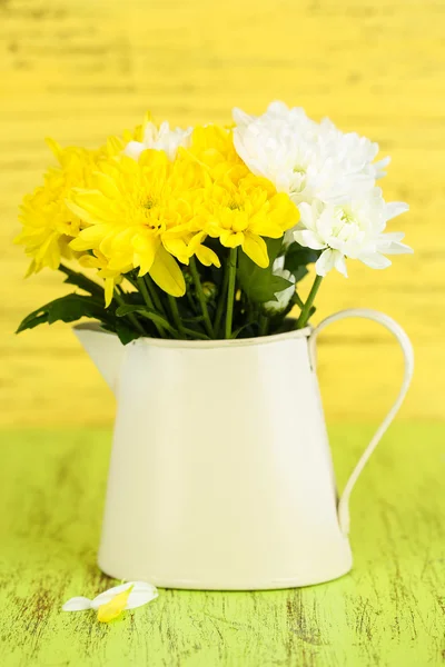 Beautiful chrysanthemum flowers in pitcher on wooden table — Stock Photo, Image