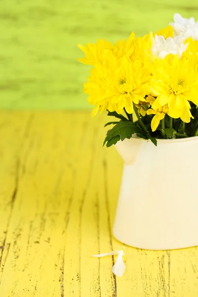 Beautiful chrysanthemum flowers in pitcher on wooden table — Stock Photo, Image