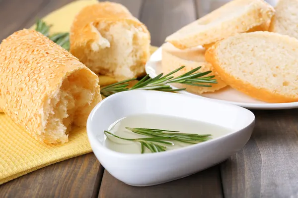 Pan fresco con aceite de oliva y romero sobre mesa de madera — Foto de Stock