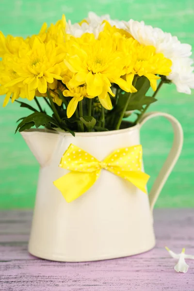 Beautiful chrysanthemum flowers in pitcher on wooden table — Stock Photo, Image