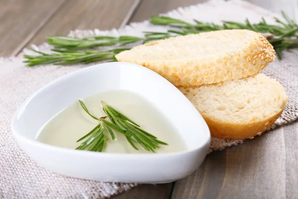 Pan fresco con aceite de oliva y romero sobre mesa de madera —  Fotos de Stock