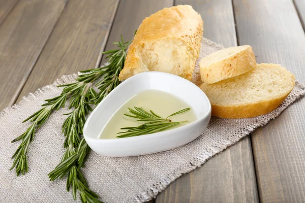 Pão fresco com azeite e alecrim sobre mesa de madeira — Fotografia de Stock