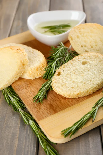 Fresh bread with olive oil and rosemary on wooden table — Stock Photo, Image