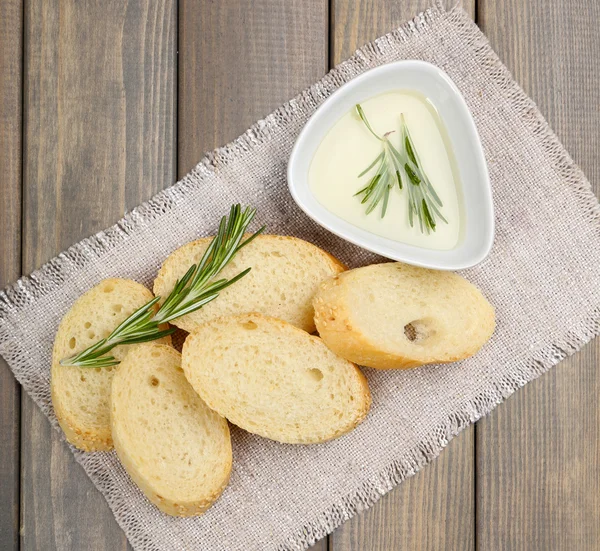 Fresh bread with olive oil and rosemary on wooden table — Stock Photo, Image