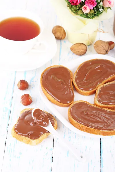 Pão com avelã de chocolate doce espalhado na placa na mesa — Fotografia de Stock