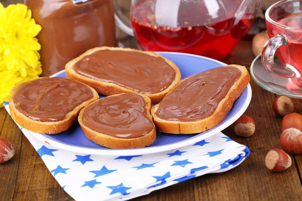 Pan con avellana de chocolate dulce extendido en el plato en la mesa — Foto de Stock