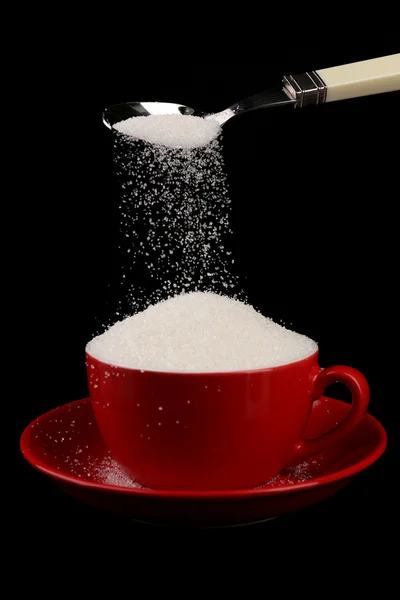 Zucker im Becher isoliert auf schwarz — Stockfoto