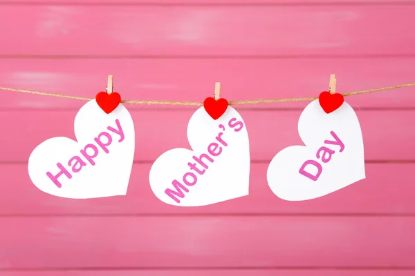 Feliz Dia das Mães mensagem escrita em corações de papel sobre fundo rosa — Fotografia de Stock