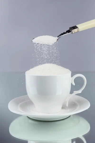 Socker i koppen på grå bakgrund — Stockfoto