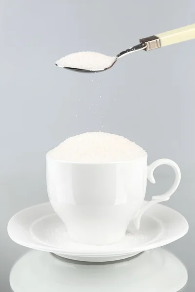 회색 배경에 컵 설탕 — 스톡 사진