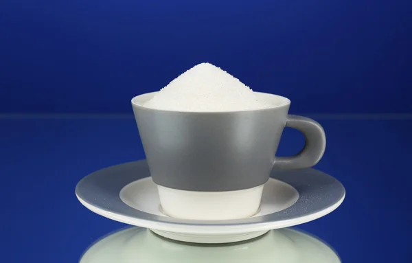 Açúcar na xícara no fundo azul — Fotografia de Stock