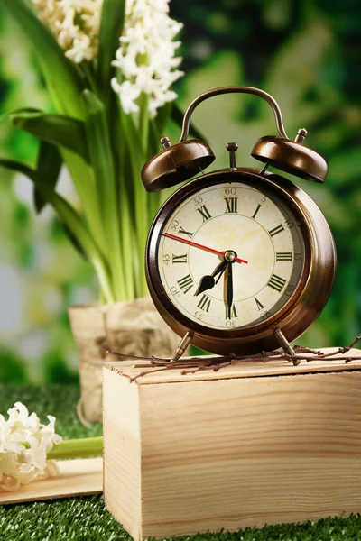 Reloj despertador sobre hierba verde, sobre fondo natural — Foto de Stock