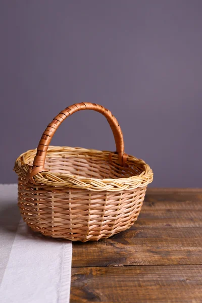 Panier en osier vide sur table en bois, sur fond sombre — Photo