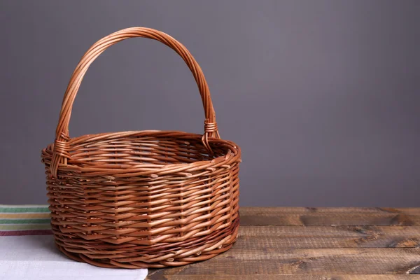 Lege rieten mand op houten tafel, op donkere achtergrond — Stockfoto