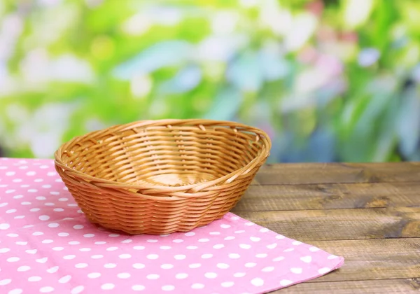 明るい背景上の木製テーブルに空の枝編み細工品バスケット — ストック写真