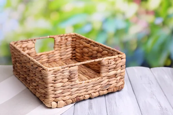 Empty wicker basket on wooden table, on bright background — Stock Photo, Image