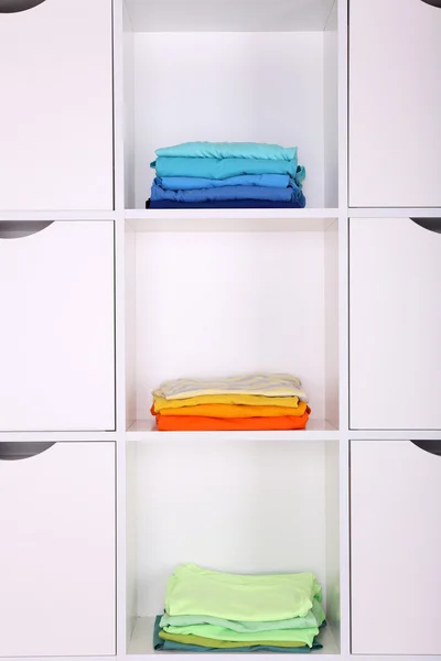 Estantes blancos con ropa de colores de cerca — Foto de Stock