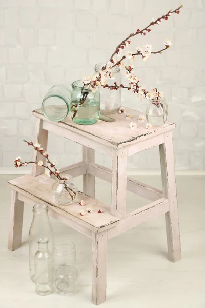 Beautiful apricot blossom in transparent jars on grey wall background — Stock Photo, Image