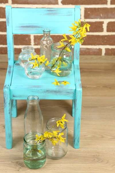 Beautiful Forsythia blossom in transparent jars on brick wall background — Stock Photo, Image