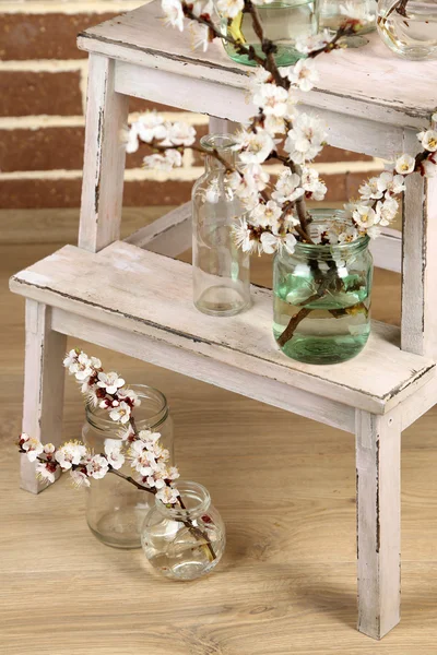 Beautiful apricot blossom in transparent jars on brick wall background — Stock Photo, Image