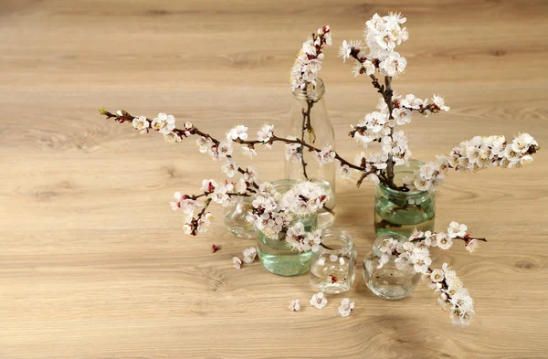 木製の背景上の透明な瓶で美しいアンズの花 — ストック写真