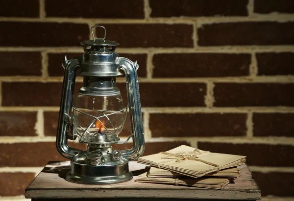 Burning kerosene lamp and letters on brick wall background — Stock Photo, Image