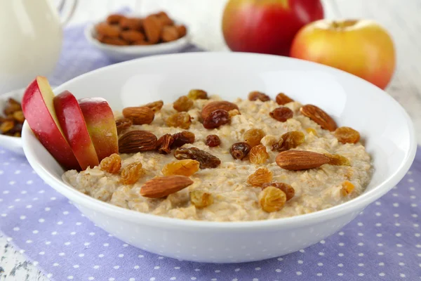 Tasty oatmeal with raisins and apples on wooden table — Stock Photo, Image