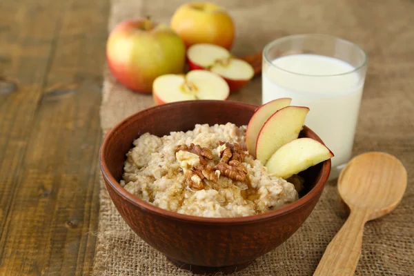 Tasty oatmeal with nuts and apples on wooden table — Stock Photo, Image