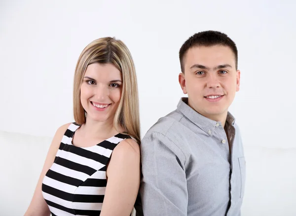 Loving couple sitting on sofa, on light background — Stock Photo, Image