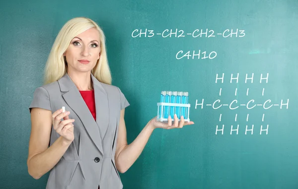 Chemistry teacher explaining formula written on blackboard to her pupils — Stock Photo, Image